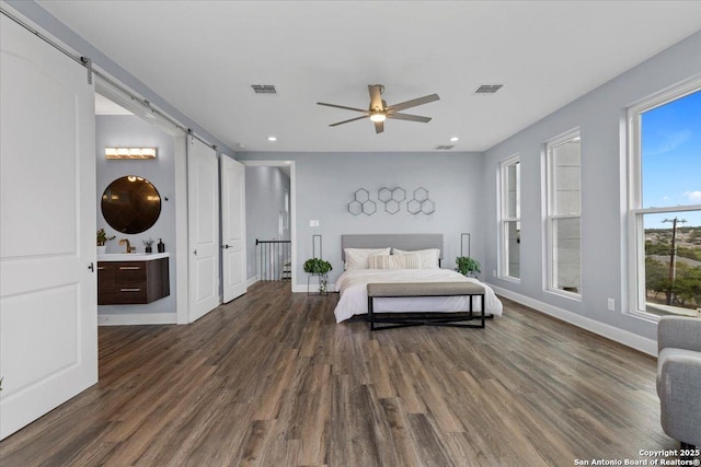 bedroom featuring baseboards, a barn door, visible vents, and wood finished floors