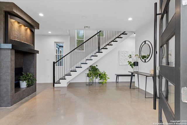 entryway with recessed lighting, visible vents, a fireplace, and stairs