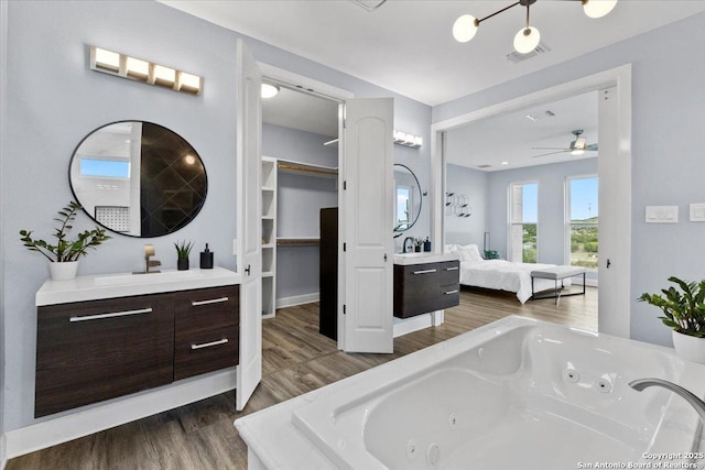 bathroom featuring visible vents, ensuite bathroom, vanity, wood finished floors, and a tub with jets