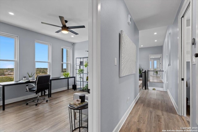 hall featuring baseboards, wood finished floors, and recessed lighting