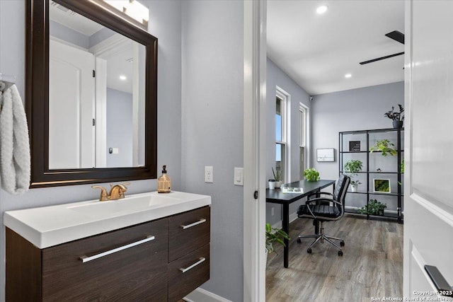 bathroom with recessed lighting, ceiling fan, vanity, wood finished floors, and baseboards