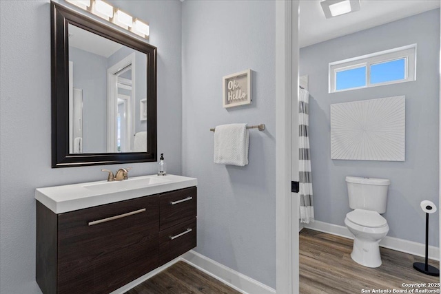 bathroom with toilet, baseboards, wood finished floors, and vanity