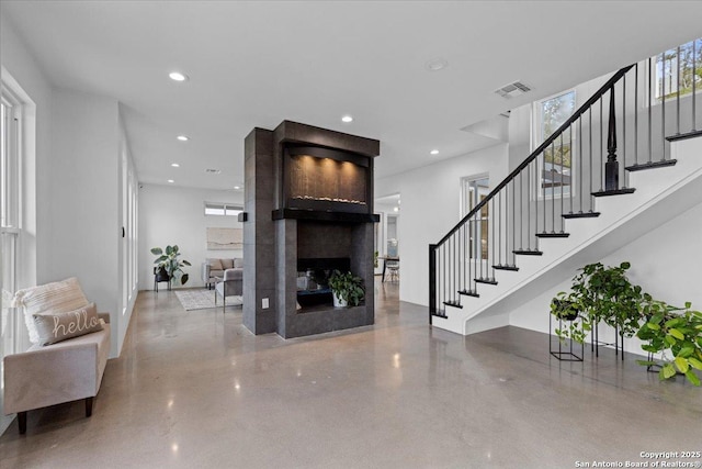 interior space with recessed lighting, visible vents, a multi sided fireplace, and stairs