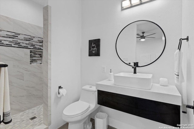 full bathroom with toilet, a tile shower, a ceiling fan, and vanity