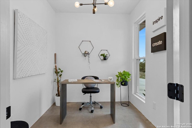 office space featuring concrete flooring and a notable chandelier