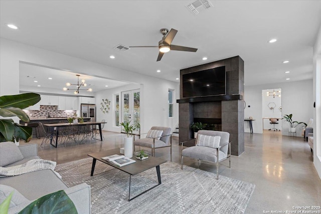 living area with a tiled fireplace, visible vents, and recessed lighting