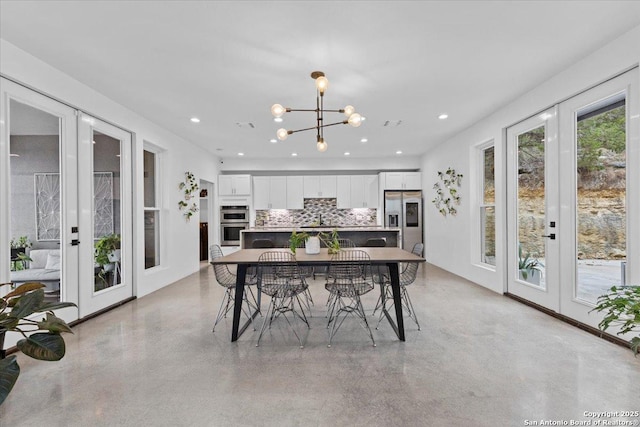 dining space with a notable chandelier, french doors, finished concrete flooring, and recessed lighting