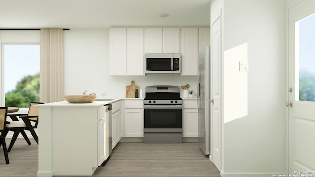 kitchen with appliances with stainless steel finishes, a wealth of natural light, light wood-type flooring, and white cabinetry