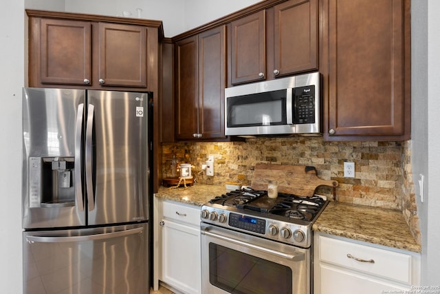 kitchen featuring stainless steel appliances, white cabinetry, light stone counters, and decorative backsplash