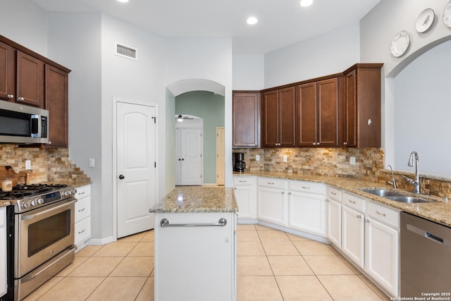 kitchen featuring arched walkways, stainless steel appliances, a sink, and visible vents