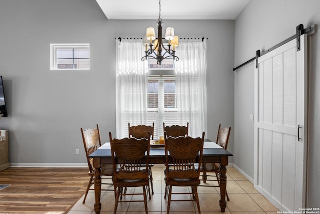 dining area featuring a notable chandelier, light wood finished floors, baseboards, and a barn door