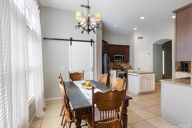 dining area with arched walkways, a barn door, light tile patterned floors, and visible vents