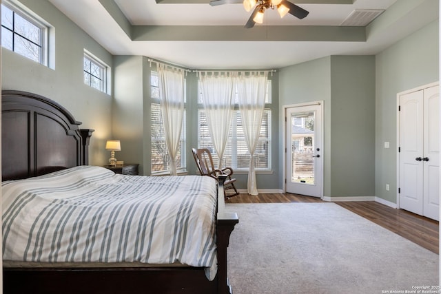 bedroom with visible vents, baseboards, a raised ceiling, and wood finished floors