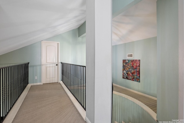 hall with vaulted ceiling, carpet flooring, and visible vents