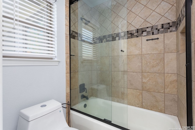 bathroom featuring bath / shower combo with glass door and toilet