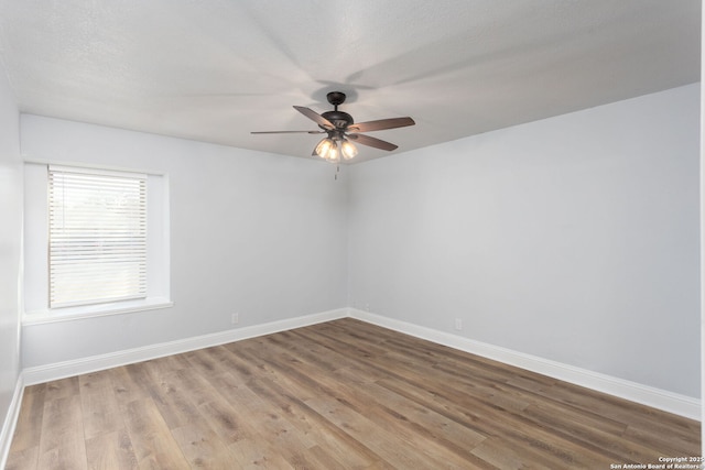 spare room with ceiling fan, wood finished floors, and baseboards