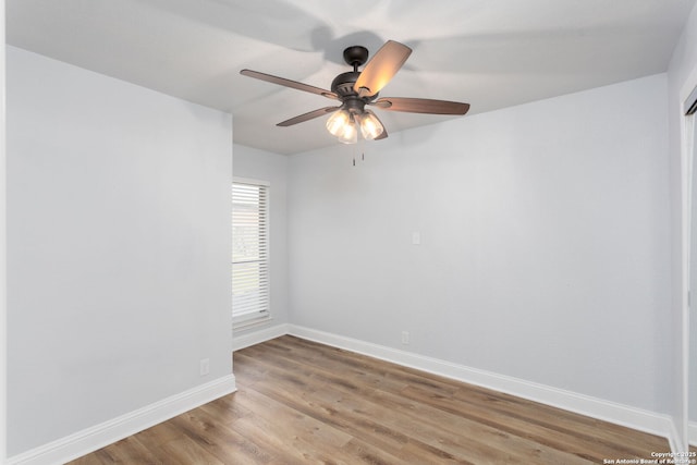 empty room with wood finished floors, a ceiling fan, and baseboards