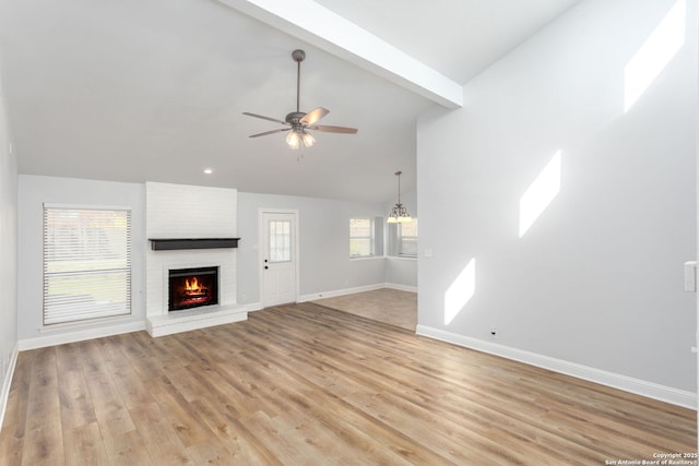 unfurnished living room with vaulted ceiling with beams, a brick fireplace, light wood-type flooring, and baseboards