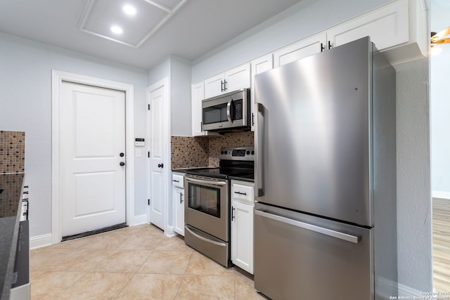 kitchen featuring light tile patterned floors, white cabinetry, appliances with stainless steel finishes, decorative backsplash, and dark countertops