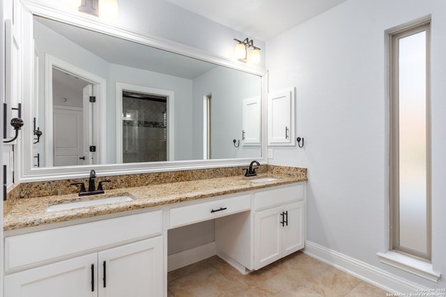 bathroom featuring a sink, a tile shower, baseboards, and double vanity