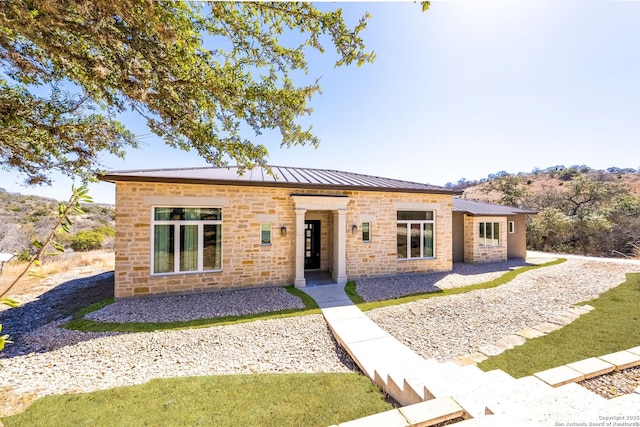 view of front of home featuring metal roof, a standing seam roof, and stone siding