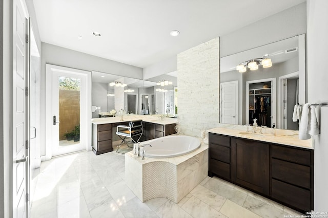 bathroom featuring a garden tub, two vanities, a sink, visible vents, and a walk in closet