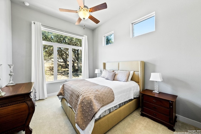 bedroom with a ceiling fan, light colored carpet, multiple windows, and baseboards