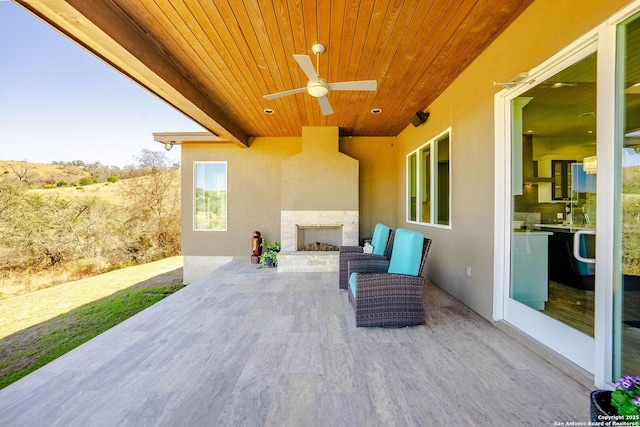 view of patio / terrace with an outdoor fireplace and a ceiling fan