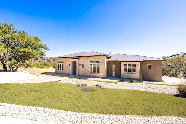 view of front of property with stone siding, a standing seam roof, metal roof, and a front lawn