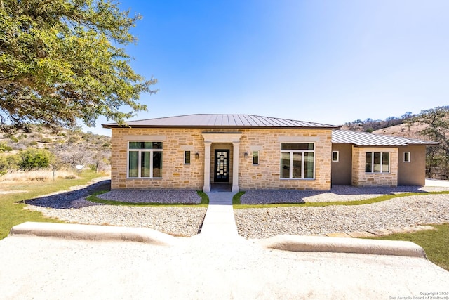 view of front of house with stone siding, a standing seam roof, and metal roof