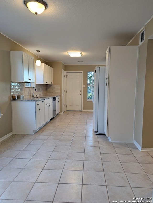 kitchen with visible vents, decorative backsplash, freestanding refrigerator, a sink, and dishwasher