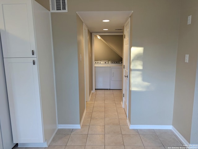 corridor featuring light tile patterned floors, washing machine and dryer, visible vents, and baseboards