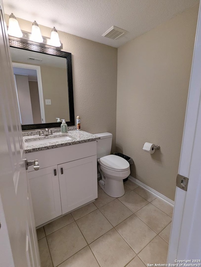 half bath with visible vents, toilet, a textured ceiling, vanity, and tile patterned flooring