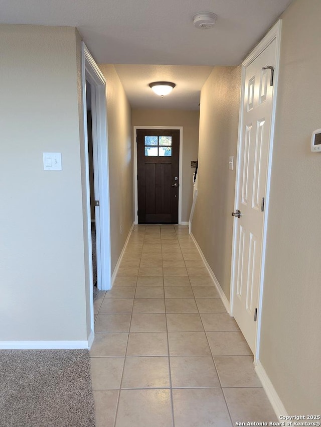 hallway featuring light tile patterned flooring and baseboards