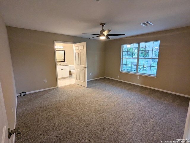 unfurnished bedroom featuring visible vents, carpet flooring, ceiling fan, ensuite bath, and baseboards