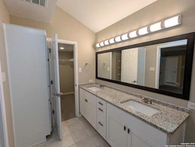 bathroom with vaulted ceiling, double vanity, a sink, and tile patterned floors