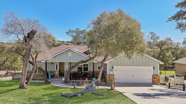 view of front of house featuring a front yard, driveway, covered porch, a garage, and board and batten siding