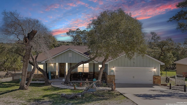 view of front of house featuring board and batten siding, fence, concrete driveway, covered porch, and a garage