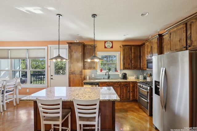 kitchen featuring a kitchen island, concrete flooring, pendant lighting, appliances with stainless steel finishes, and backsplash