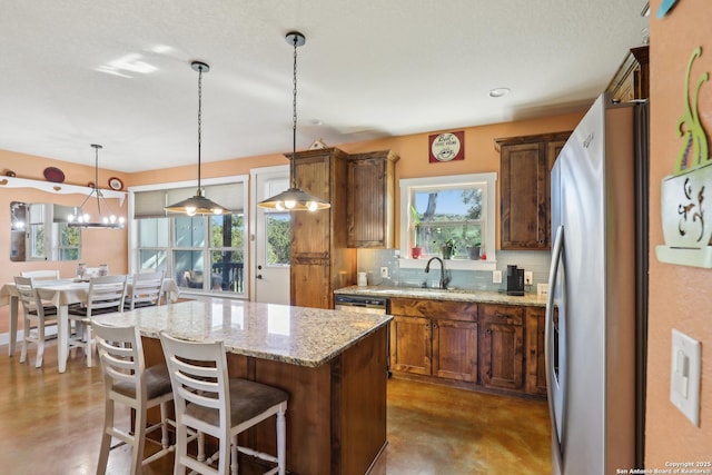 kitchen featuring a center island, finished concrete floors, pendant lighting, light stone counters, and decorative backsplash