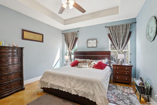 bedroom featuring a tray ceiling, baseboards, and ceiling fan