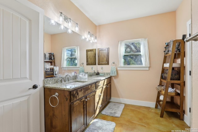 bathroom featuring double vanity, baseboards, and a sink