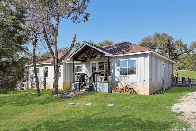 view of front of house featuring board and batten siding, a front lawn, and fence