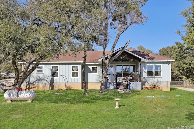 rear view of house featuring a yard, board and batten siding, and fence