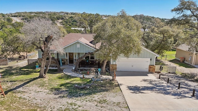 view of front of home with driveway, a porch, fence, board and batten siding, and an attached garage