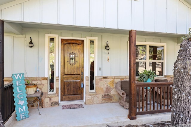 property entrance with a porch, stone siding, and board and batten siding