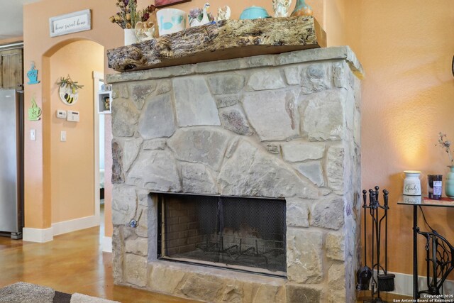 interior details featuring wood finished floors, freestanding refrigerator, arched walkways, a fireplace, and baseboards