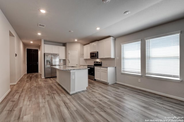 kitchen featuring stainless steel appliances, white cabinets, a sink, and visible vents