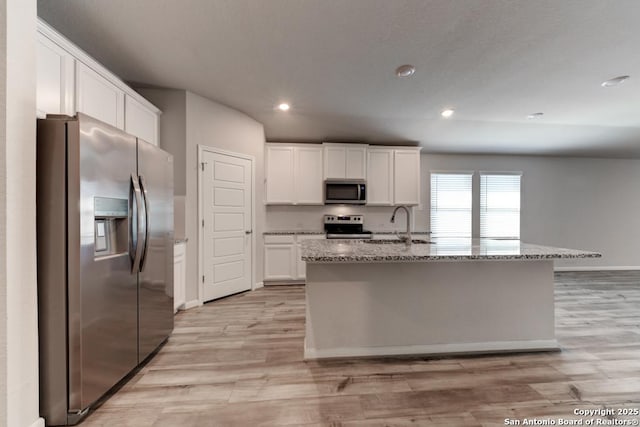 kitchen featuring appliances with stainless steel finishes, light wood-type flooring, white cabinets, and light stone countertops