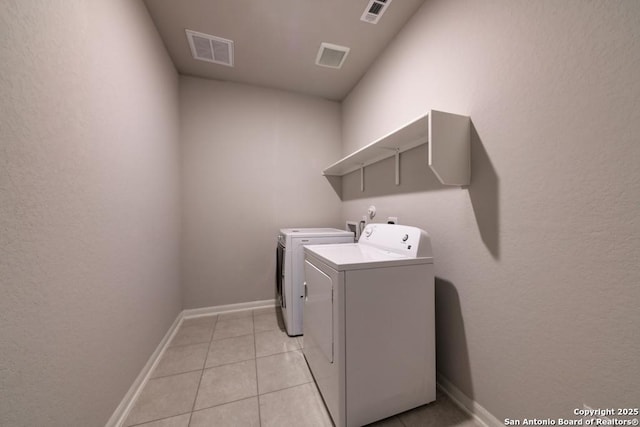 washroom featuring laundry area, washing machine and dryer, visible vents, and light tile patterned flooring